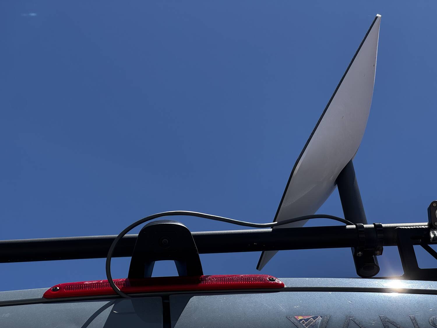 Starlink dish deployed on the roof rack viewed from below with 360 camera beside it