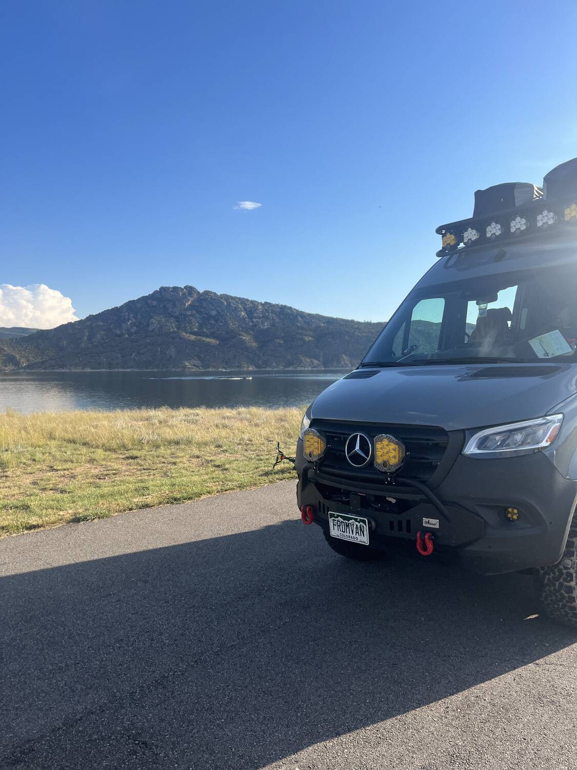 Sprinter front corner at a Colorado mountain lake with light bar visible