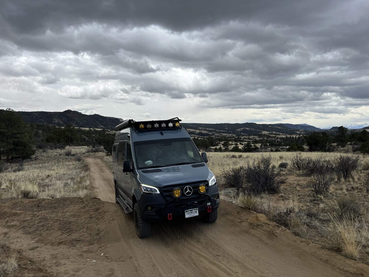 Sprinter on a stormy dirt road with the Sangre de Cristo range beyond