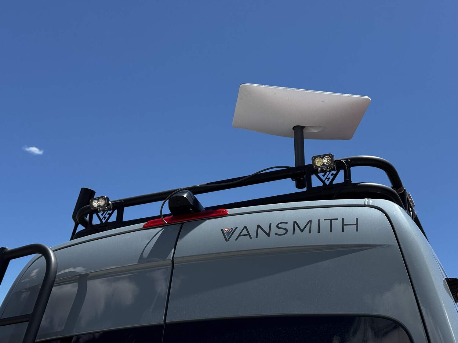Starlink dish deployed on the roof rack against blue sky