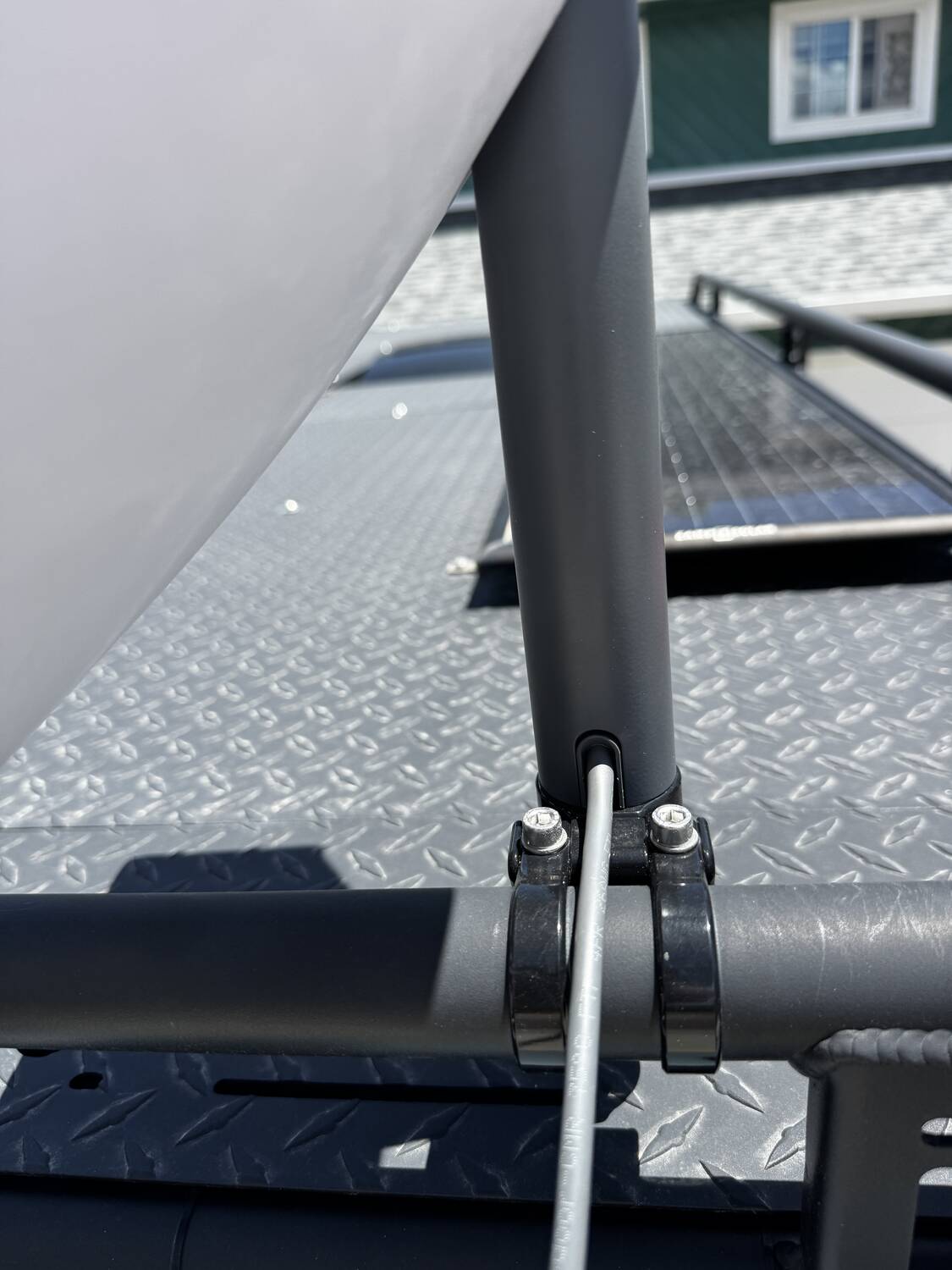 Close-up of the Starlink dish mount clamp bracket bolted to the roof rack rail