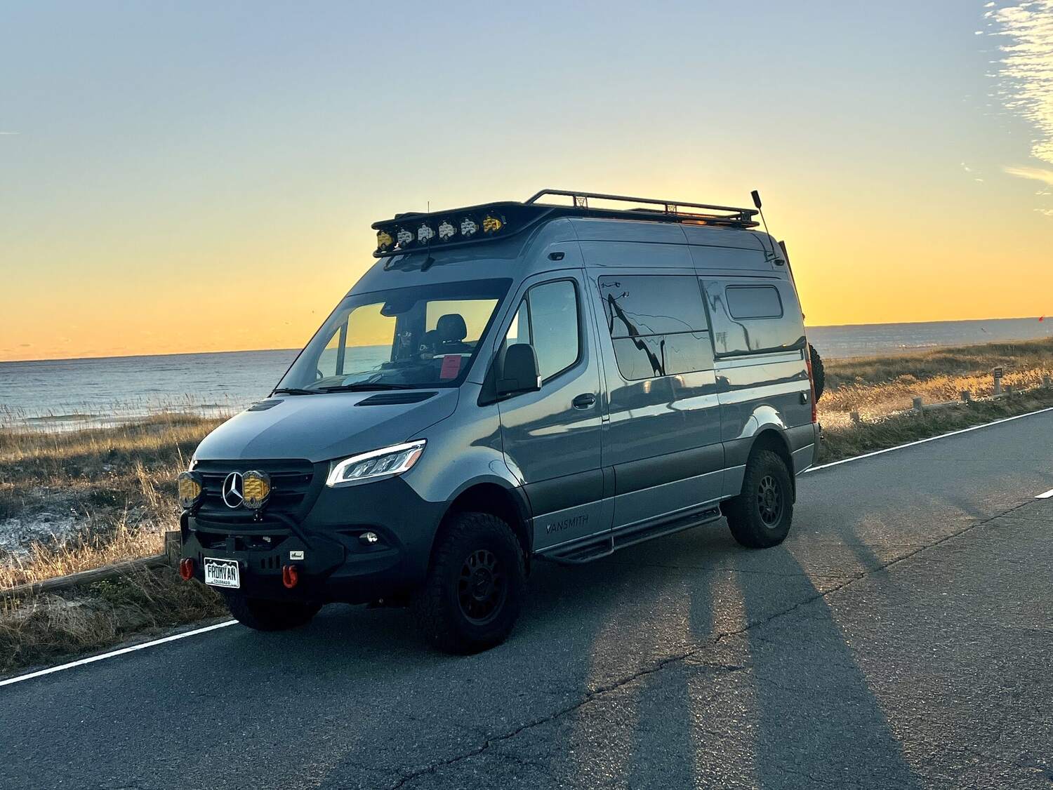 Sprinter parked on a coastal road at sunset over the ocean