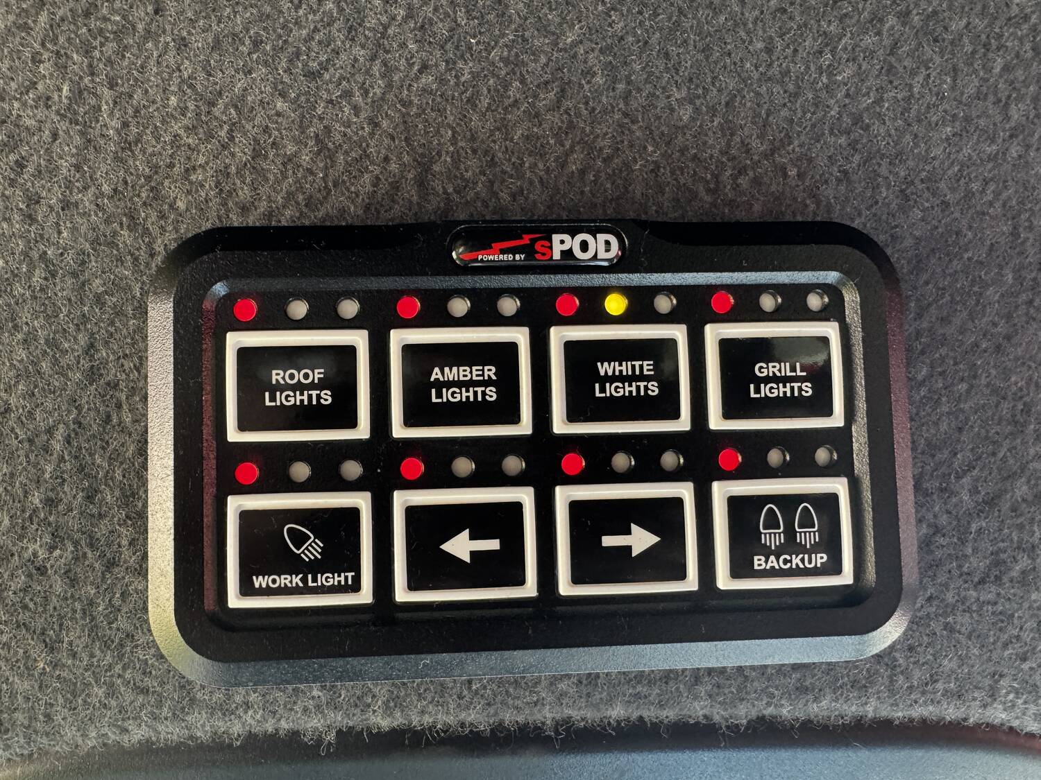 sPOD BantamX 8-switch panel labeled Roof, Amber, White, Grill lights with work light, turn arrows and backup