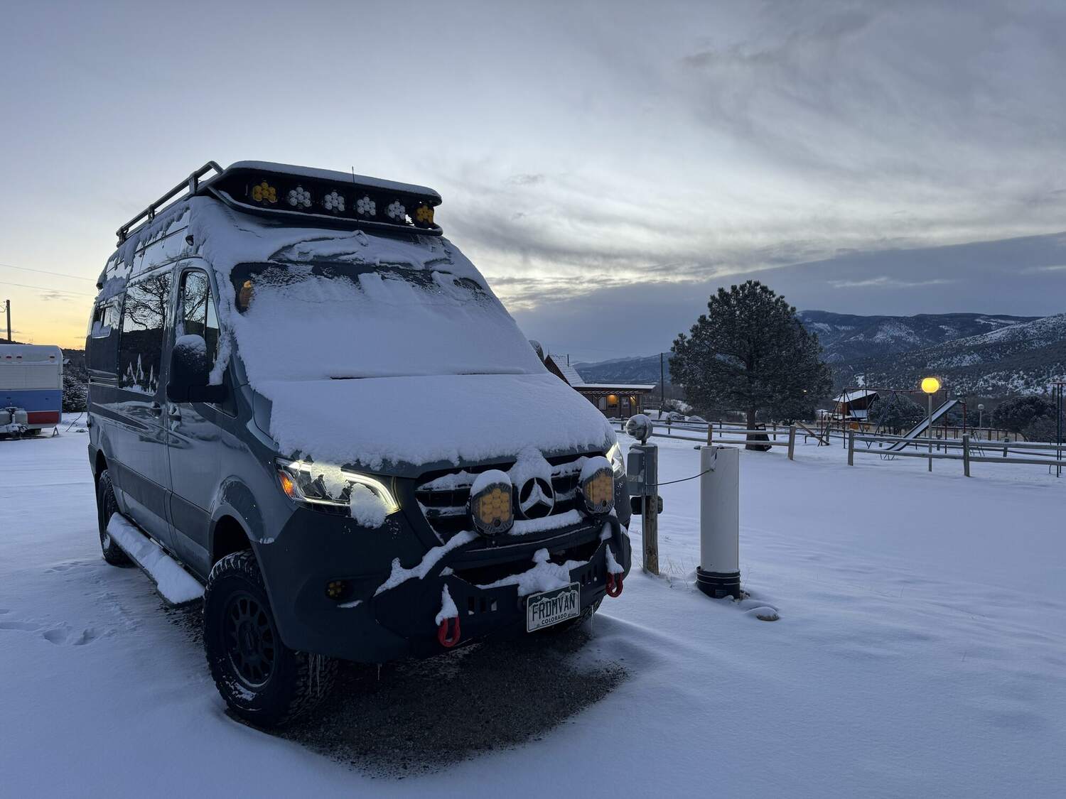 Sprinter parked in fresh snow at dusk in the Colorado high country