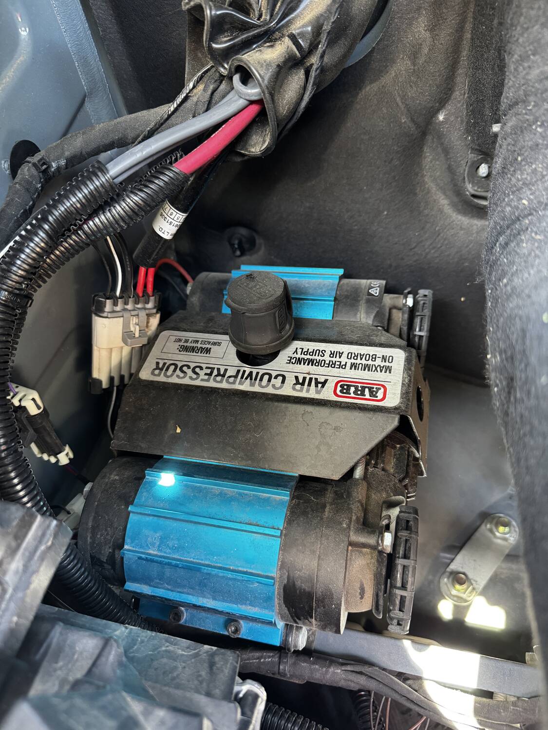 ARB Twin air compressor mounted under the hood with wiring loom