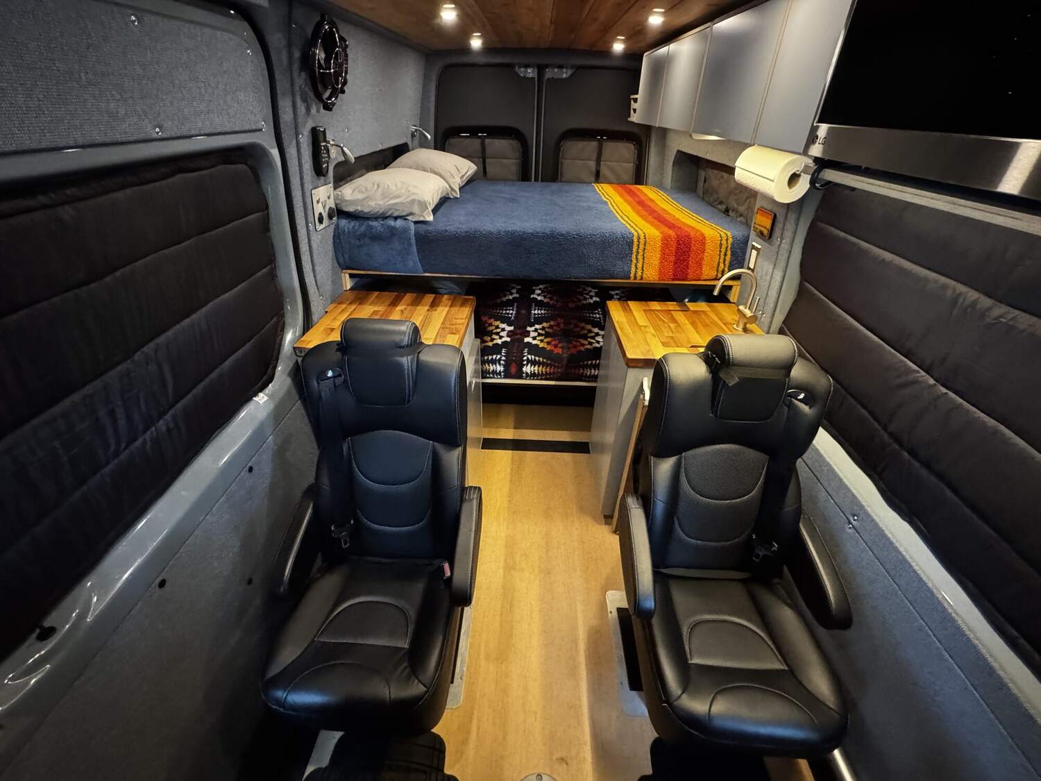 Interior looking toward the rear: captain's chairs, galley, and bunk