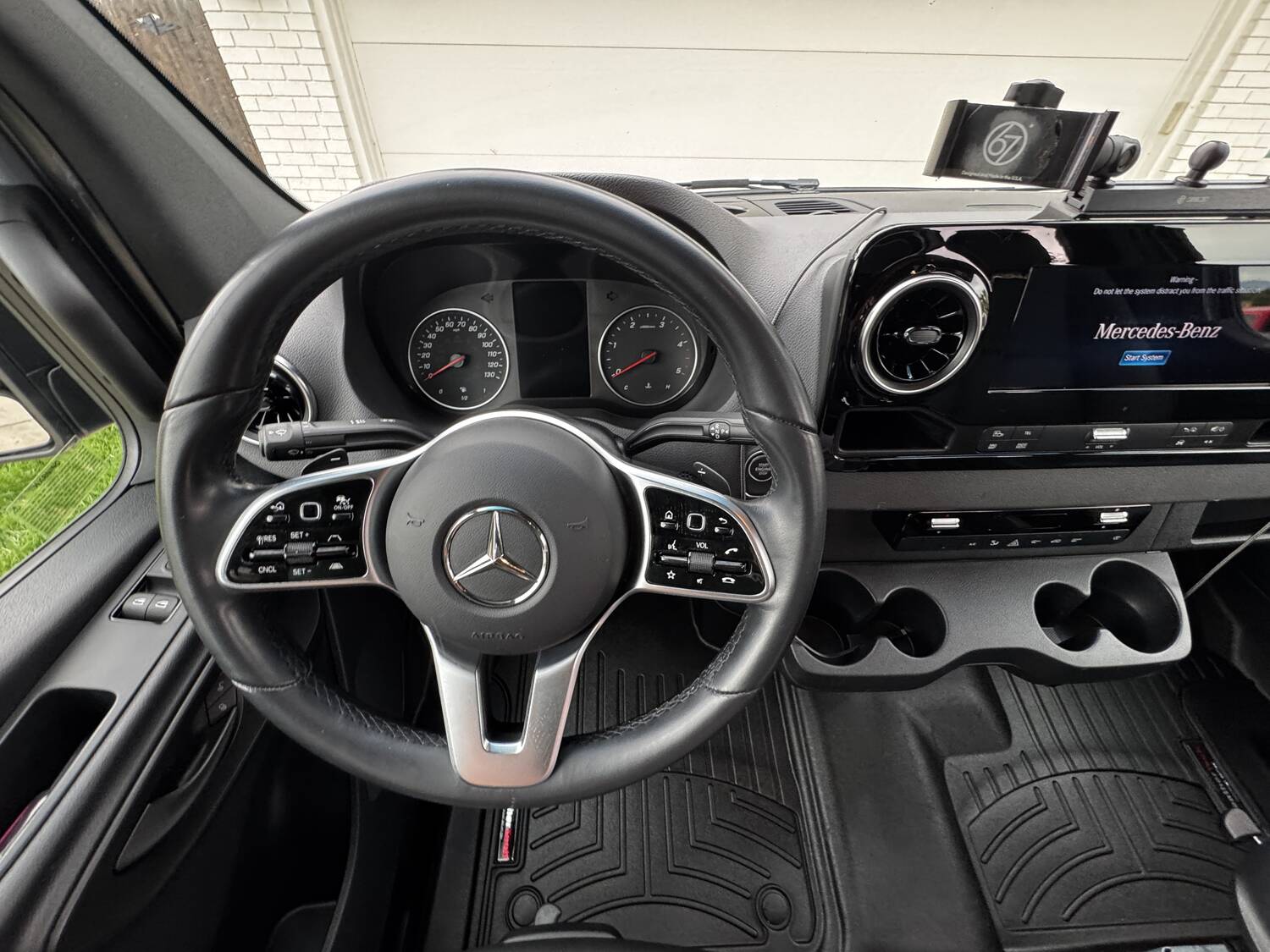 Steering wheel and analog gauge cluster with MBUX screen to the right