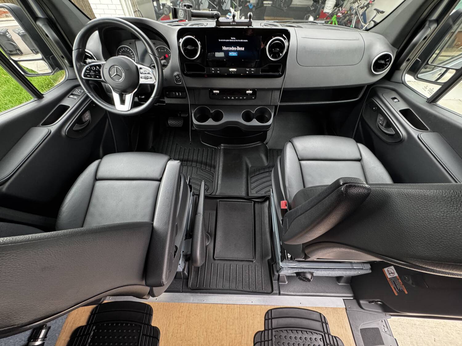 Sprinter cab wide view: dash, MBUX screen, both swiveling front seats and floor mats